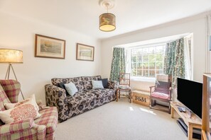 A living room with a sofa, armchairs, a television, and a window with curtains. - 3 Bed in Walberswick (oc-e30479) (Walberswick)
