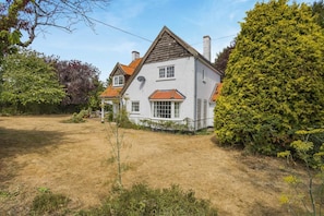 A two-story house with a white exterior and red-tiled roof, surrounded by a grassy yard and various trees. - 3 Bed in Walberswick (oc-e30479) (Walberswick)