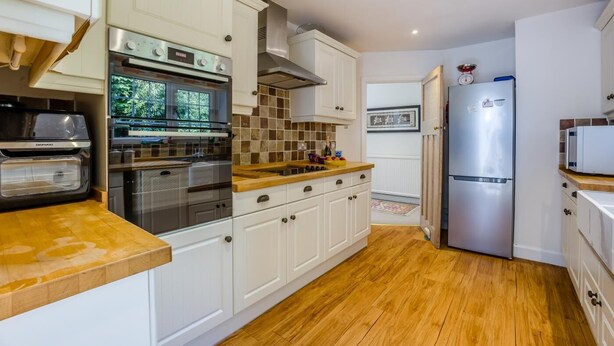Eine moderne Küche mit weißen Schränken, einem Einbauofen, einer Mikrowelle und einem Edelstahl-Kühlschrank.