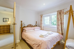 A bedroom with a bed, bedside lamps, a window with curtains, a wooden wardrobe, and a bedside table. - 3 Bed in Walberswick (oc-e30479) (Walberswick)