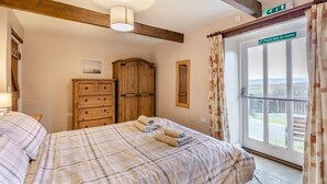 A bedroom with a bed, a wooden wardrobe, a window with a view, and a door with a push bar. - 2 Bed in Eggleston (oc-s30453) (Middleton-in-Teesdale)