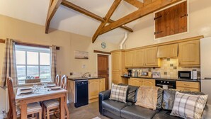 A cozy kitchen with wooden cabinets, a dining area with a table set for four, and a leather sofa. - 2 Bed in Eggleston (oc-s30453) (Middleton-in-Teesdale)