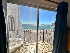 A balcony with a view of the sea, a white cushioned chair, and a metal railing. - Beach condo close to everything (San Carlos Nuevo Guaymas)