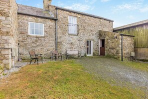 A stone building with a gravel driveway, a wooden door, and three benches. - 2 Bed in Eggleston (oc-l30452) (Middleton-in-Teesdale)