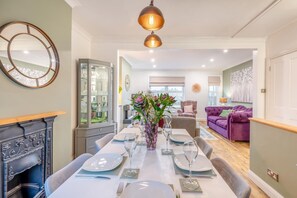 A dining area with a long table set for four, a fireplace, and a view of the living room. - 3 Bed in Rye (oc-q30369) (Rye)