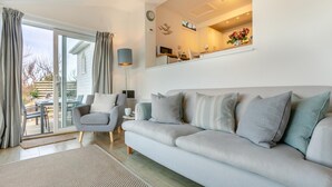 A modern living room with a sofa, armchair, and a dining area with a table and chairs.