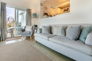A modern living room with a sofa, armchair, and a dining area with a table and chairs. - 2 Bed in Sennen (oc-t30543) (Sennen)