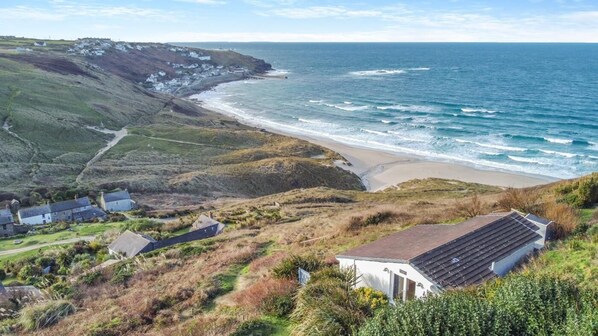 A coastal landscape with a beach, houses, and a cliff overlooking the sea. - 2 Bed in Sennen (oc-t30543) (Sennen)