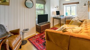 Una sala de estar con un sofá, una mesa de centro, una televisión y un escritorio con una computadora.