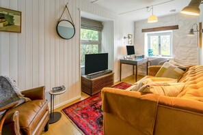 A living room with a sofa, a coffee table, a television, and a desk with a computer. - 2 Bed in Newlyn (oc-t30565) (Newlyn)