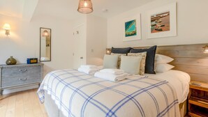 Un dormitorio con cama, mesitas de noche, cómoda y obras de arte en las paredes.