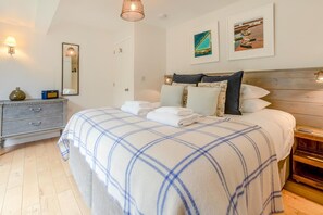 A bedroom with a bed, bedside tables, a dresser, and artwork on the walls. - 2 Bed in Newlyn (oc-t30565) (Newlyn)