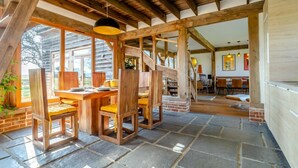 A rustic wooden dining area with a stone floor, wooden chairs, and a table set for two. - 3 Bed in Mundesley (oc-o30555) (Mundesley)