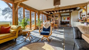 A spacious living area with large windows, a wooden ceiling, and a cozy seating arrangement including a sofa, armchair, and a dining table. - 3 Bed in Mundesley (oc-o30555) (Mundesley)