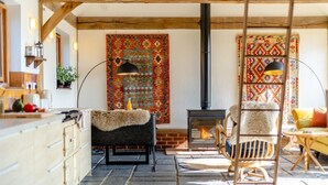 A cozy living room with a fireplace, patterned rugs, and rustic furniture. - 3 Bed in Mundesley (oc-o30555) (Mundesley)