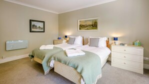 A bedroom with a bed, bedside tables, a dresser, and a wall-mounted heater.
