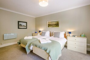 A bedroom with a bed, bedside tables, a dresser, and a wall-mounted heater.