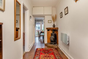 A hallway with a wooden floor, a red patterned rug, a black stove, and a door leading to a dining area. - 2 Bed in Briston (oc-s30561) (Briston)