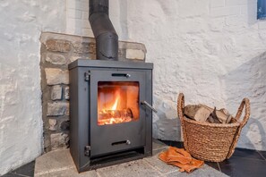 A wood-burning stove with a fire burning inside, placed against a stone wall. - 1 Bed in Frampton (oc-r30566) (Frampton)