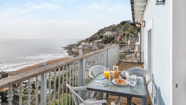 Ein Balkon mit Frühstückstisch mit Blick auf den Ozean.