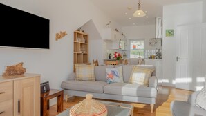 Ein Wohnzimmer mit einer Couch, einem Fernseher und einer Holzkommode.