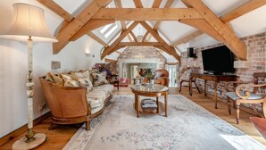 A spacious loft with exposed wooden beams, a cozy seating area with a sofa and chairs, a dining table, and a television. - 4 Bed in Wareham (oc-r30563) (Wareham)