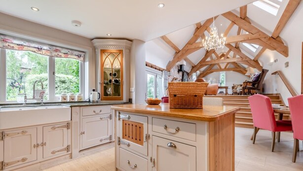 A spacious kitchen with a central island, wooden beams on the ceiling, and a view of the outdoors through large windows. - 4 Bed in Wareham (oc-r30563) (Wareham)