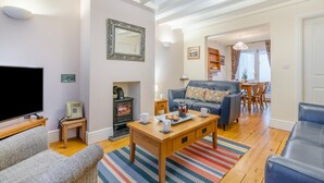 Ein gemütliches Wohnzimmer mit Fernseher, Kamin, einer Couch und einem Essbereich mit Tisch und Stühlen.