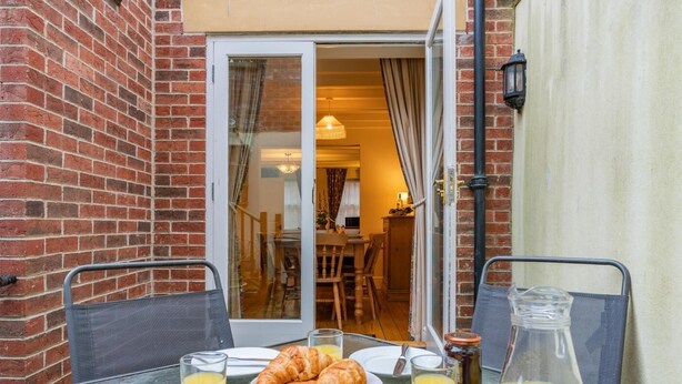 Ein Frühstückstisch mit Croissants, Orangensaft und Stühlen.