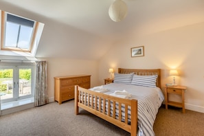 A bedroom with a bed, wooden dresser, bedside tables, a window, and a ceiling light. - 3 Bed in Burton Bradstock (oc-s30572) (Burton Bradstock)