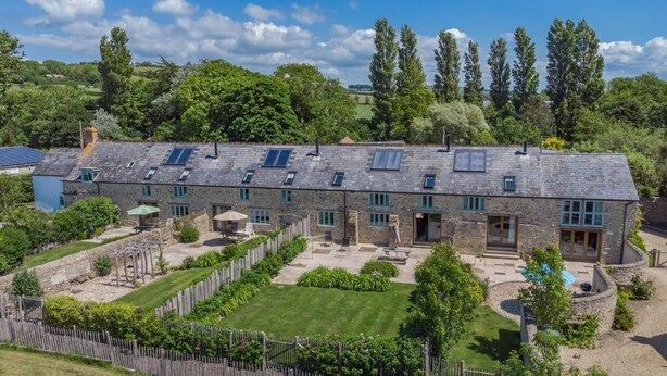 A stone building with multiple rooms, a fenced garden, and a clear sky. - 3 Bed in Burton Bradstock (oc-s30572) (Burton Bradstock)