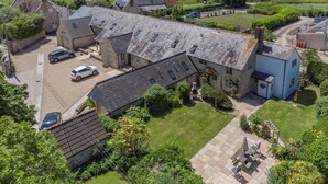 A large stone building with multiple rooms, a parking area, and a well-maintained lawn. - 3 Bed in Burton Bradstock (oc-s30572) (Burton Bradstock)