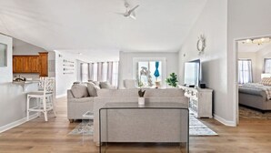 Un vaste espace de vie comprenant un grand canapé, une table à manger et une cuisine visible au fond.