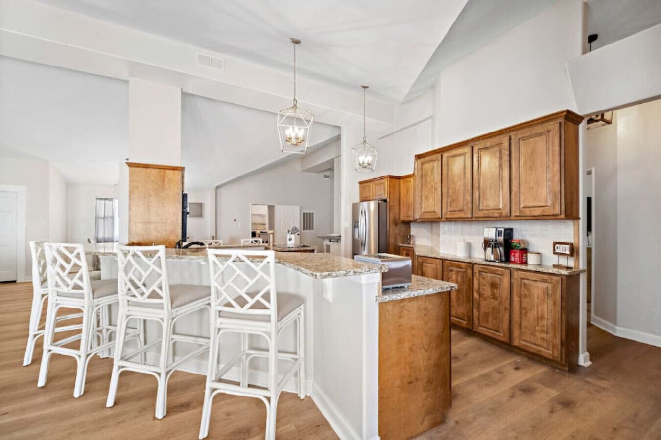 Una cocina moderna con armarios de madera, una isla central con taburetes altos e iluminación colgante.