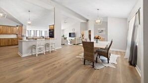 Une cuisine spacieuse avec des meubles en bois, un îlot central doté de tabourets et un éclairage suspendu.