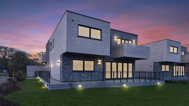 Una casa moderna de varios pisos con techo plano, ventanas amplias y un césped bien cuidado.