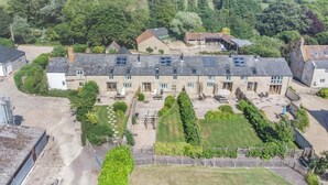 A large stone building with multiple rooms, a courtyard with seating, and a view of the surrounding countryside. - 3 Bed in Burton Bradstock (oc-c30571) (Burton Bradstock)