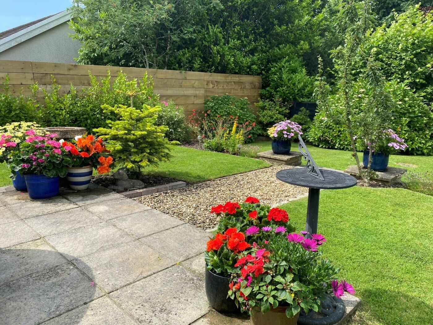 A garden with potted plants, a stone pathway, and a solar-powered bird bath.