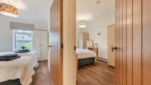 Ein Schlafzimmer mit zwei Betten, einem Fenster mit Ausblick, Holzboden und einem Kleiderschrank.