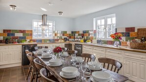 A spacious kitchen with a long island, white cabinetry, and colorful backsplash tiles. - 8 Bed in Ynys (oc-c29818) (Ynys)