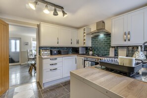 A modern kitchen with white cabinets, a black countertop, and a green backsplash.