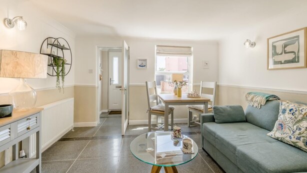 A living room with a sofa, a glass coffee table, and a dining area with a table and chairs.