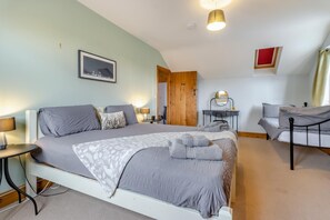 A bedroom with a bed, bedside tables, a desk, and a chair.