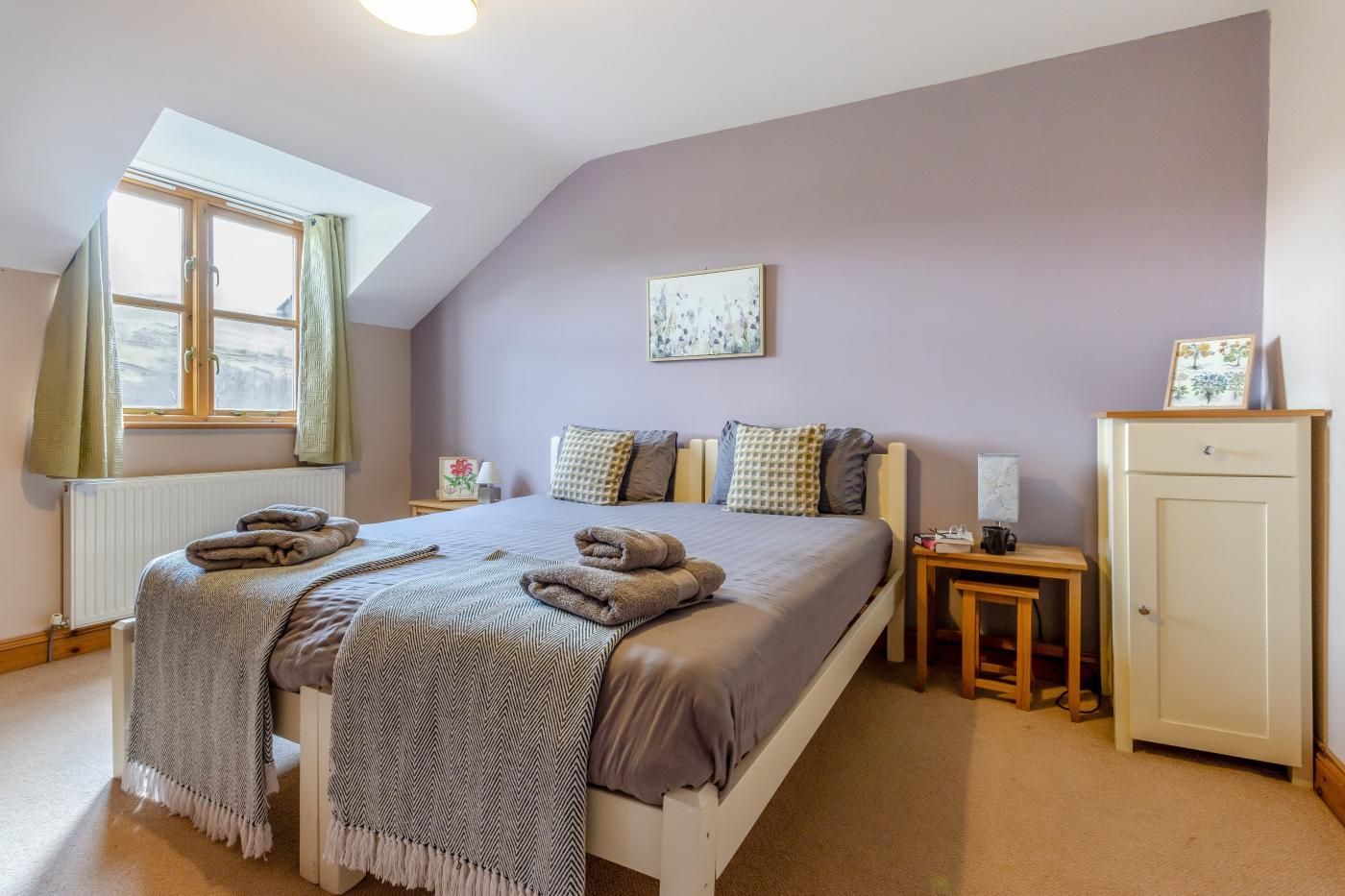 Ein Schlafzimmer mit Bett, Fenster, Heizkörper, Nachttisch und Kleiderschrank.