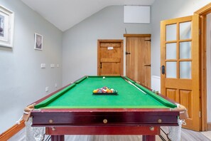 A pool table with balls and cues, a wooden door, and a framed picture on the wall.