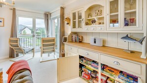 Una stanza con balcone, una scrivania con libri e un computer, e una mensola con oggetti decorativi.