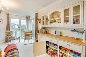 A room with a balcony, a desk with books and a computer, and a shelf with decorative items. - 2 Bed in Aviemore (oc-t30584) (Aviemore)