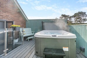 Ein Whirlpool auf einer Holzterrasse mit Glastür und Sitzbank.