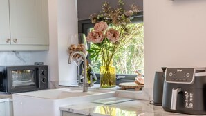 Eine moderne Küche mit Einbau-Mikrowelle, Spüle mit Wasserhahn, Blumen in einer Vase und einer Kaffeemaschine.