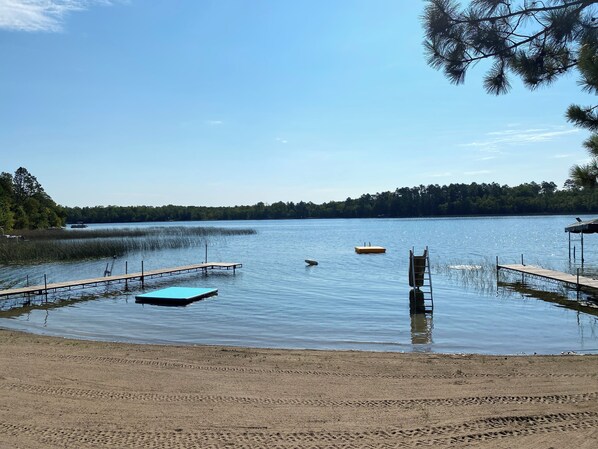 A lake with a wooden dock extending into the water, surrounded by trees.